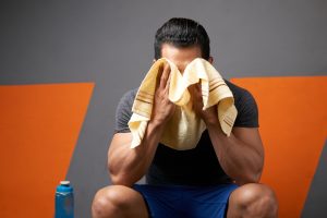 sweating man wiping away sweat with a towel